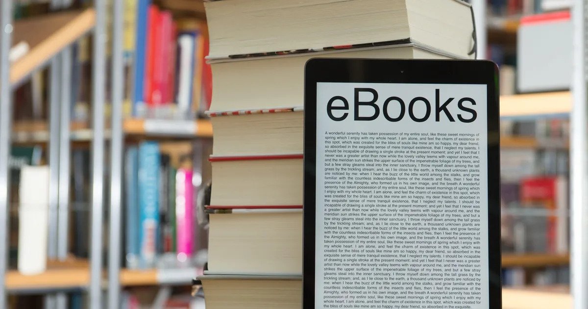 E-books on a tablet inclined against a stack of books