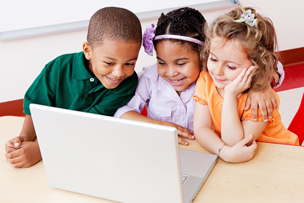 3 Kids Watching Something On A Laptop While Smiling