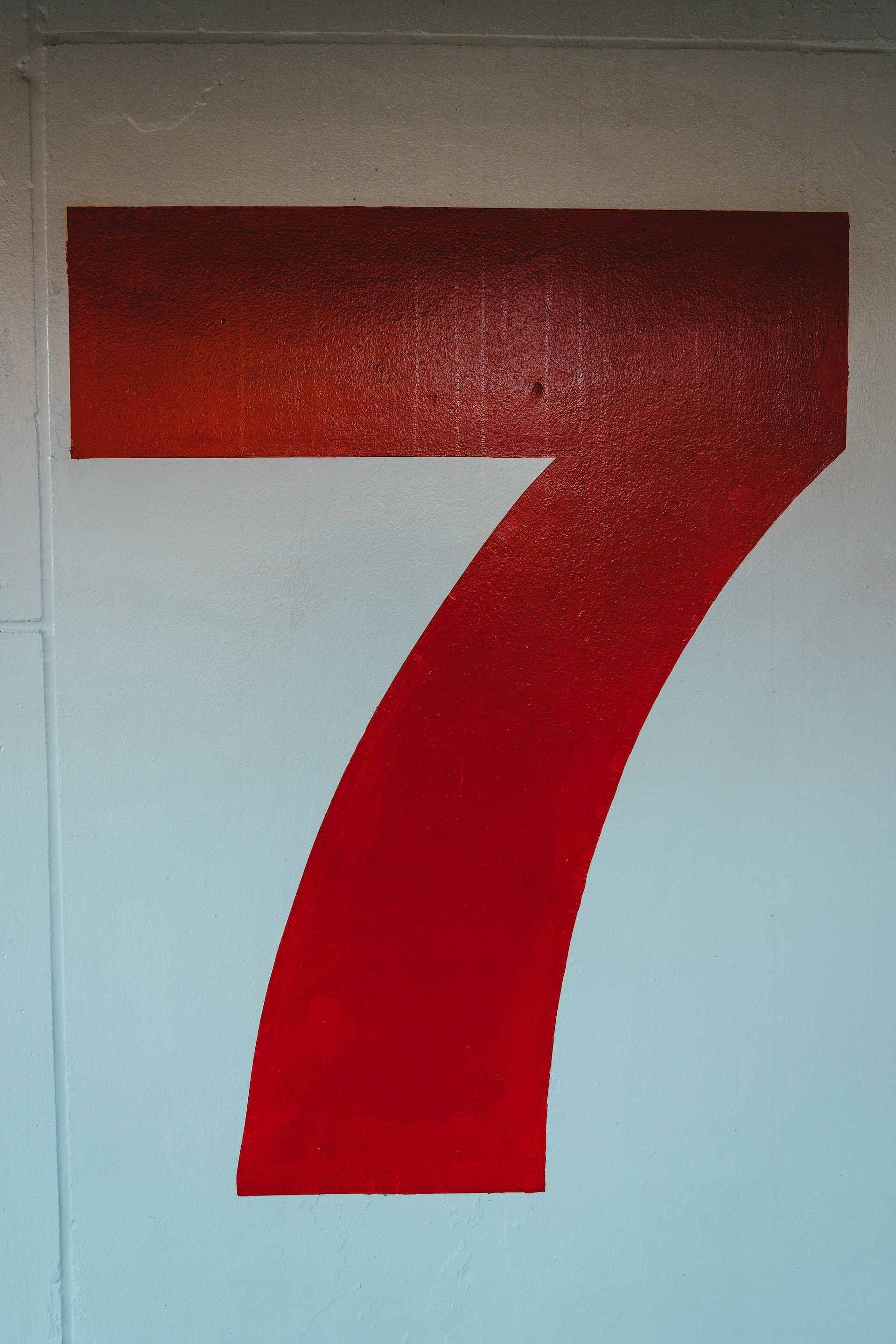Number seven painted in black over a white wall