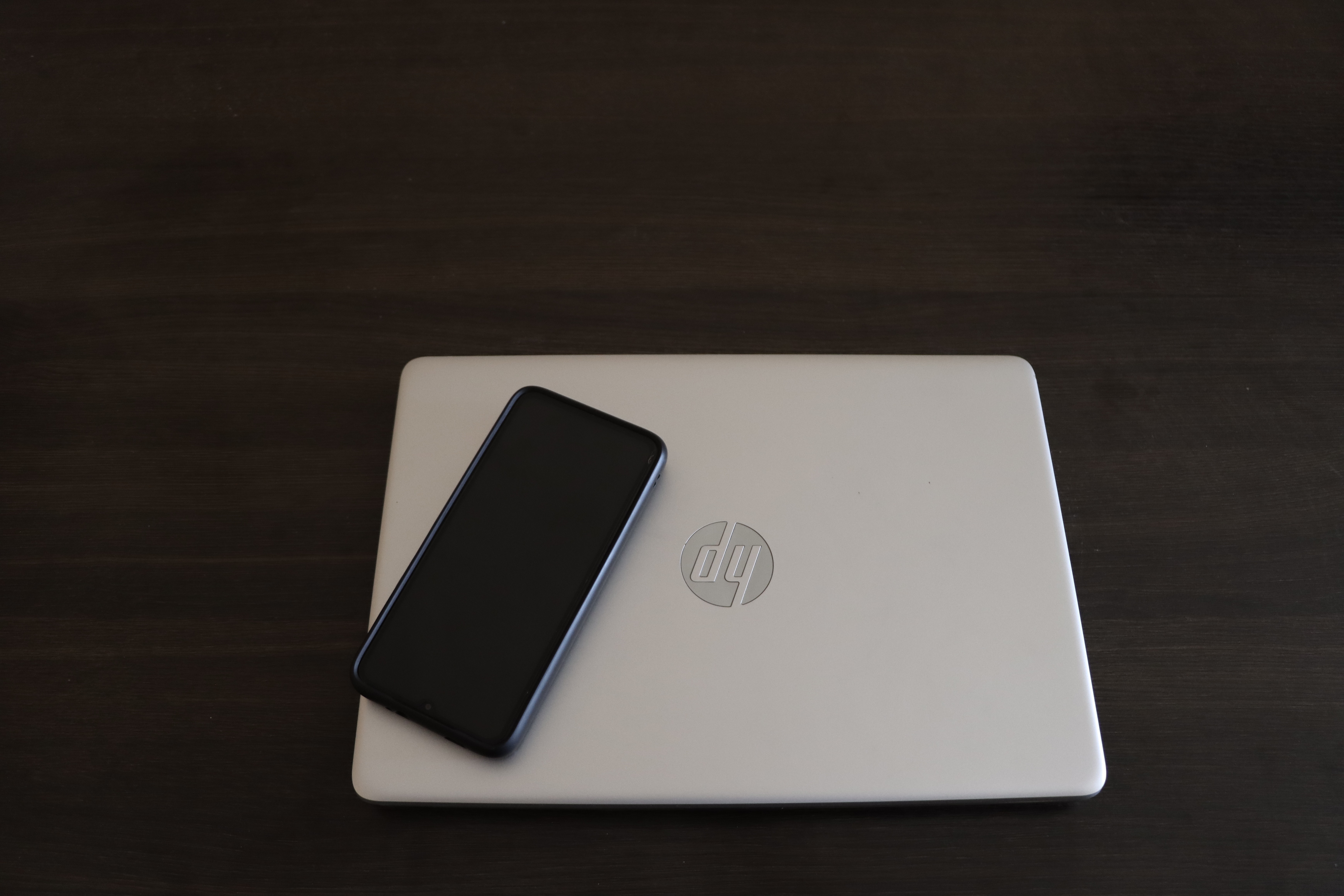 Hp envy x360 silver laptop with a smartphone on top of it