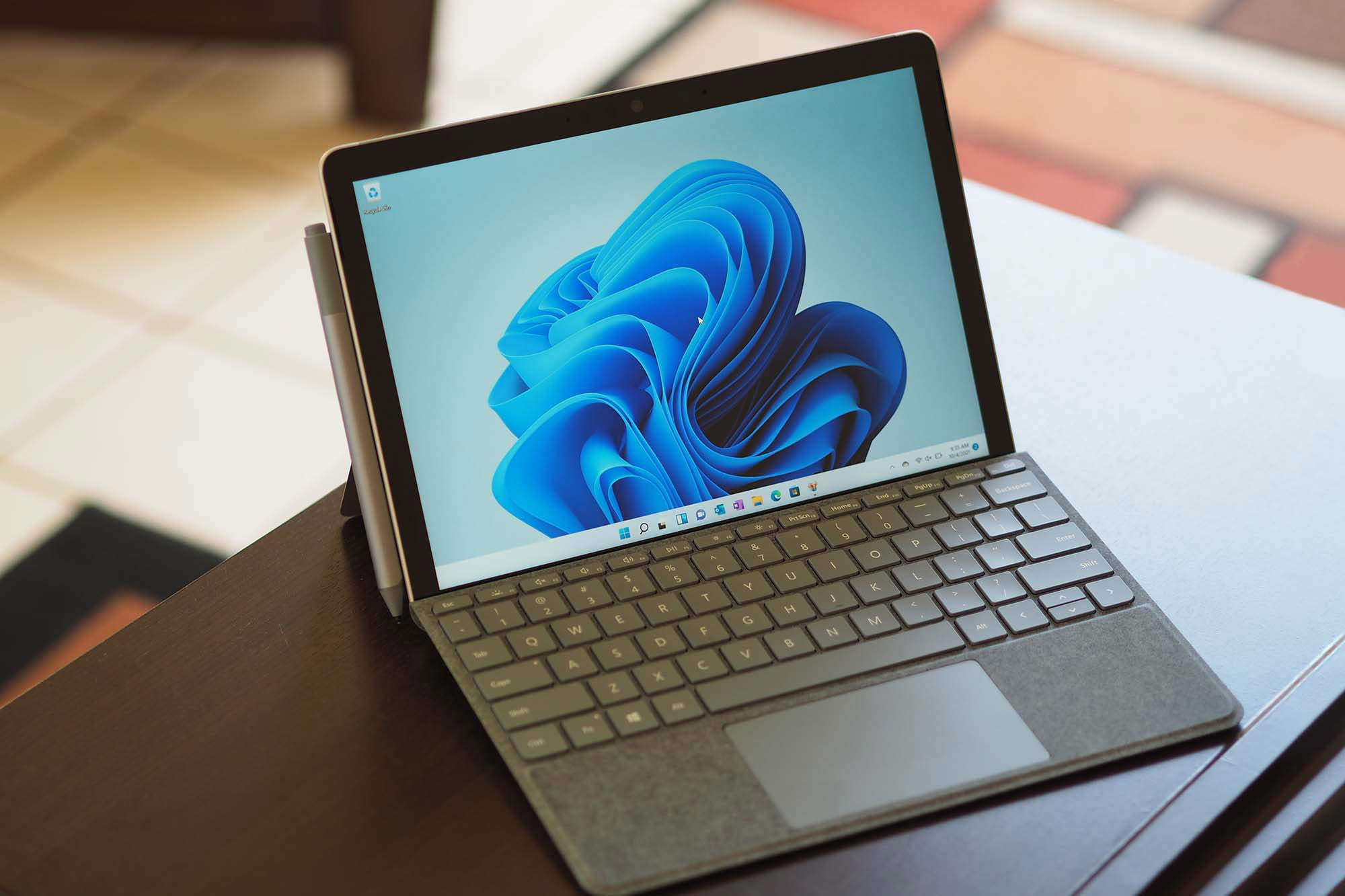 Microsoft surface go 3 with blue wallpaper on top of a wooden table